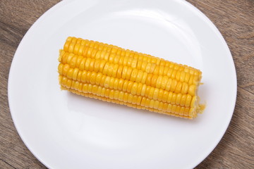 fresh boiled cob corn on a wooden plate
