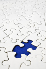 A top view image of a white jigsaw puzzle with a missing piece.