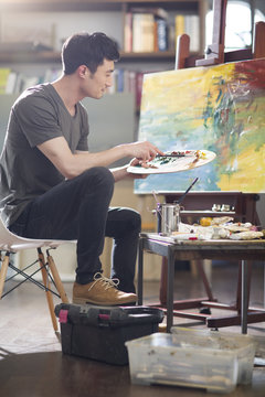 Artist painting in his studio