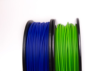 Front half-view of standing blue and green 3D printer filament spools 