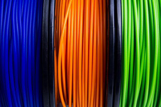 Close-up of blue, orange and green 3D printer filament spools
