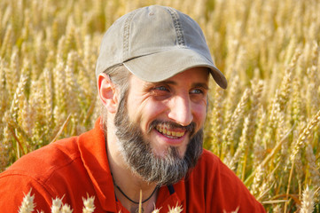 Naklejka na ściany i meble bearded man sitting in a wheat field on sunny day