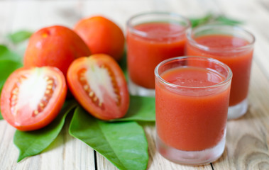 Glasses of fresh tomato juice on wooden table, closeup
