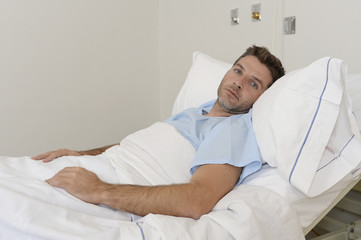 young patient man lying at hospital bed resting tired looking sad and depressed worried