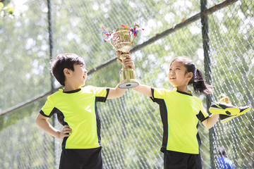 Happy children in sportswear showing their trophy