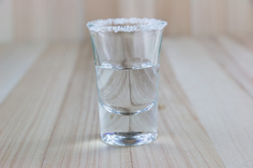 Vodka shot and salt sea on wooden table