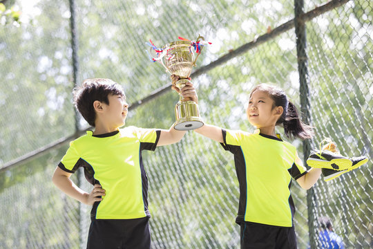 Happy children in sportswear showing their trophy