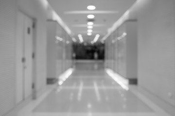 Black and white blurred long corridor in building with doors and reflections. Medical, hospital, office, hotel.