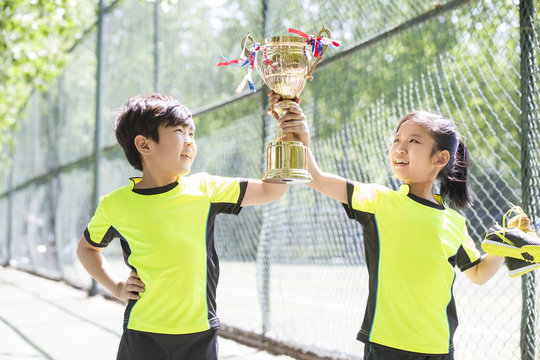 Happy children in sportswear showing their trophy