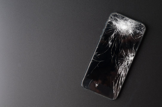Smartphone with broken screen on dark background