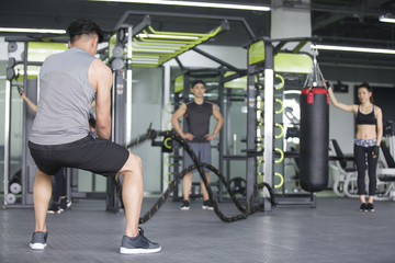 Fototapeta na wymiar Young man exercising with battling rope at gym