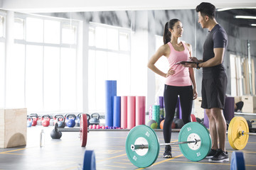 Young woman talking with trainer at gym