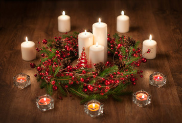 Christmas wreath with white candle, reindeer and ball on dark background