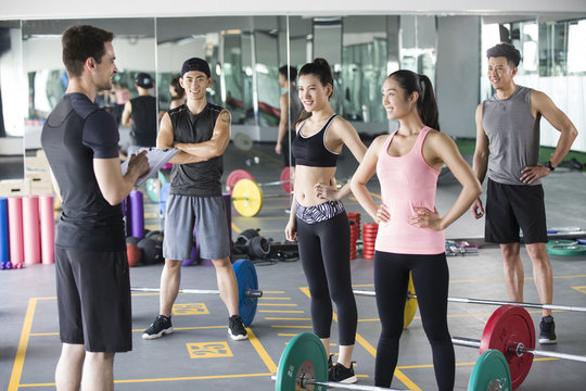 Young adult working with trainer at gym