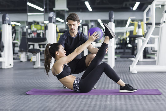 Young woman working out with trainer in gym