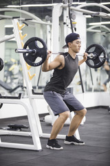 Young man lifting barbell at gym