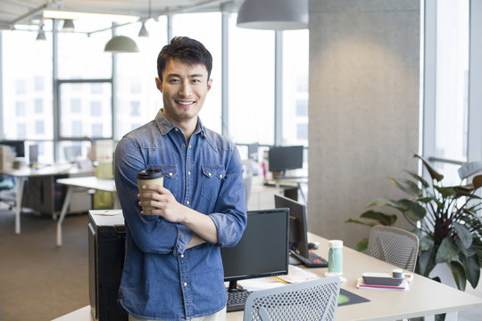 Portrait Of Young Businessman Holding Coffee Cup In Office