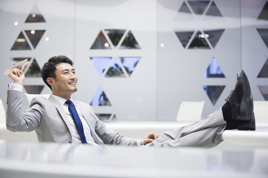 Young Businessman Flying A Paper Airplane