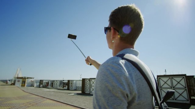 Traveller holding selfie stick and walking