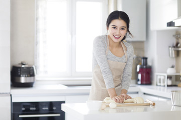 Young woman kneading dough on cutting board