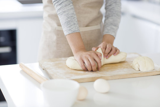 Young woman kneading dough on cutting board