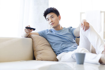 Young man watching TV at home