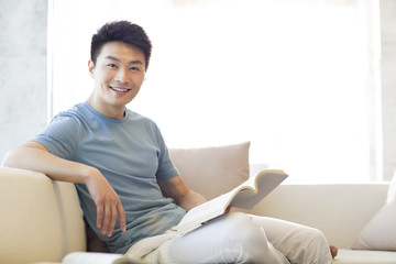 Young man reading a book on the sofa
