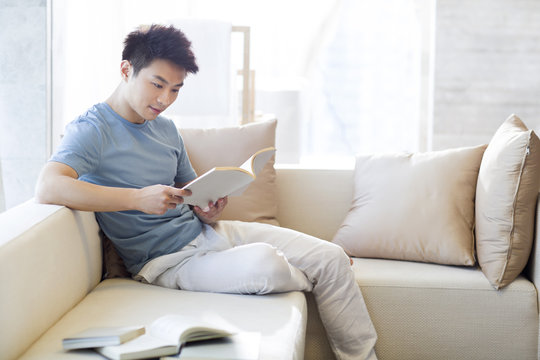 Young man reading a book on the sofa