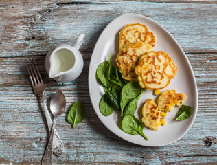 Gluten free corn fritters and fresh spinach on a wooden board, top view.