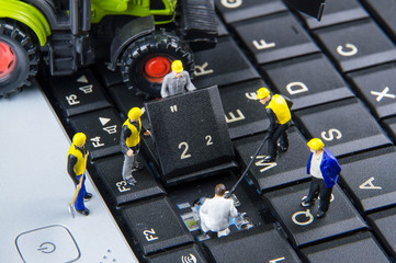 Tiny toys team of engineers repairing keyboard computer laptop.C
