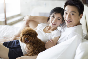 Young couple playing with a pet poodle at home