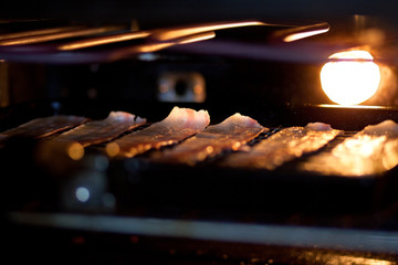 Rashers of streaky bacon being grilled in an oven.

