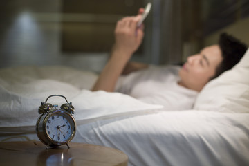 Young man using smart phone on bed in the middle of night