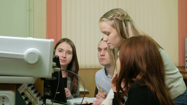 Young student engineers team work in the University of the electrical laboratory. They counsel and test oscilloscope voltmeter readings on the instruments. Future scientists