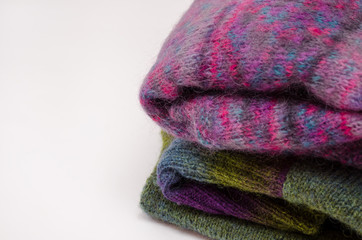 Stack of warm winter knitted sweaters on white background