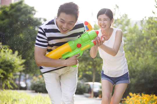 Happy young couple playing squirt guns