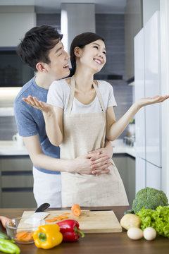 Happy young couple cooking in kitchen