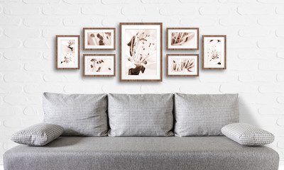  Interior decor mock up. Frames collage with floral posters on bricks textured wall, over modern couch.