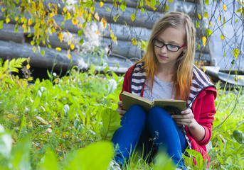 Teenager sitting in forest and reading book