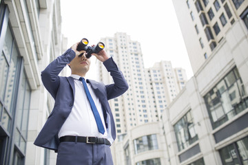 Confident businessman looking through binoculars