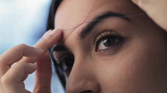 CU TU Young woman plucking eyebrows with thread