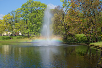 Naklejka premium The iridescent fountain on the city channel in the sunny May afternoon. Park of the Bastionny hill, Riga. Latvia