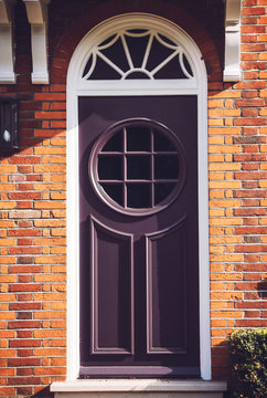 View of one vibrant purple door with round windows on London str