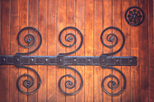 Background of close up crop wooden door with metal hinges and ri