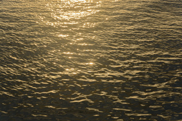 Reflection light by sunset sky on the water in the sea gold color