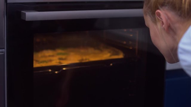 CU Young attractive female checking the cookies in the oven. 4K UHD RAW edited footage