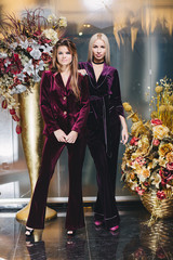 Brunette and blonde women posing in suits