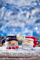 Santa Claus And Snowman Candle Holders On Snowy Wood