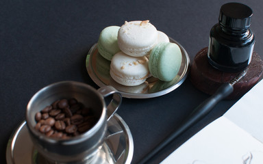 Coffee with notepad and French macarons on the darck background