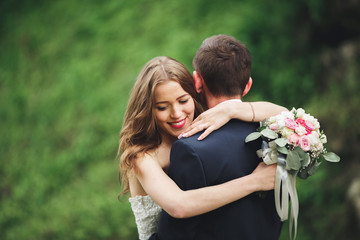 Happy wedding couple hugging and smiling each other on the background gorgeous plants in castle